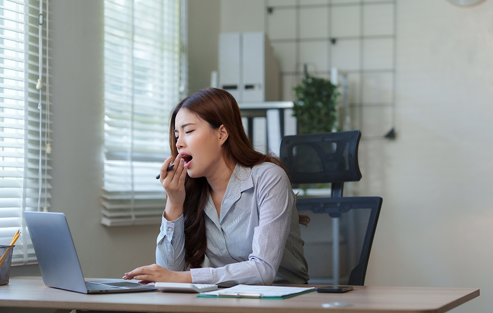 Woman experiencing persistent tiredness at work, which may be linked to thyroid issues